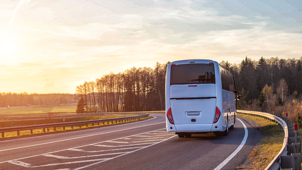 autobus bianco che viaggia in strada extraurbana non trafficata al tramonto