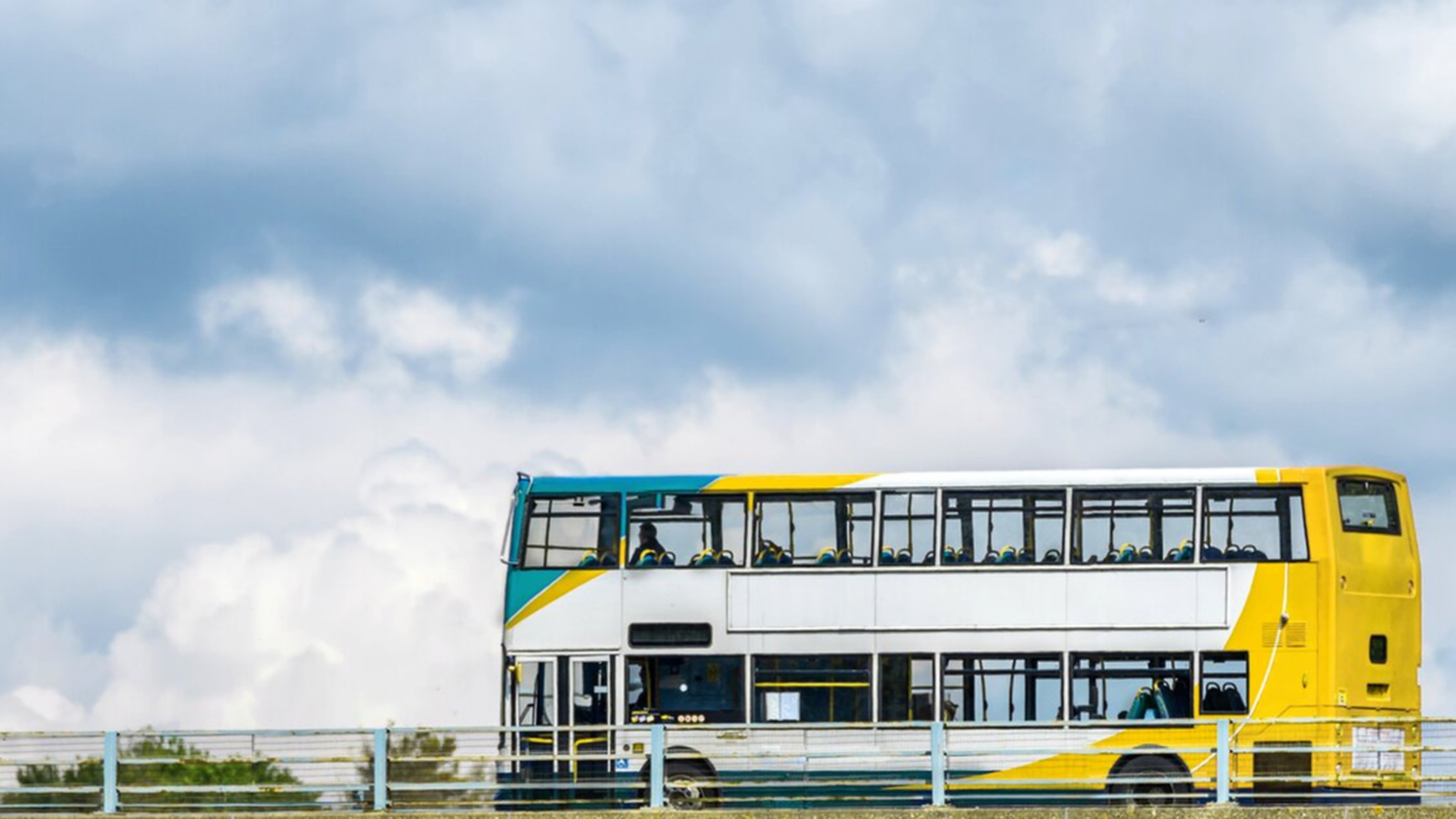 Bus per trasporto persone bianco,giallo e celeste che viaggia su strada