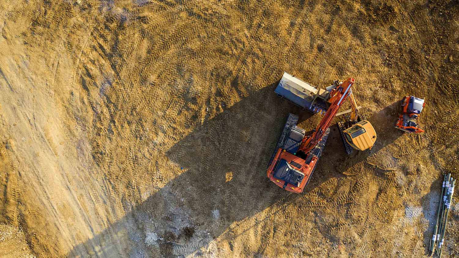 Yellow excavator digging into the dirt