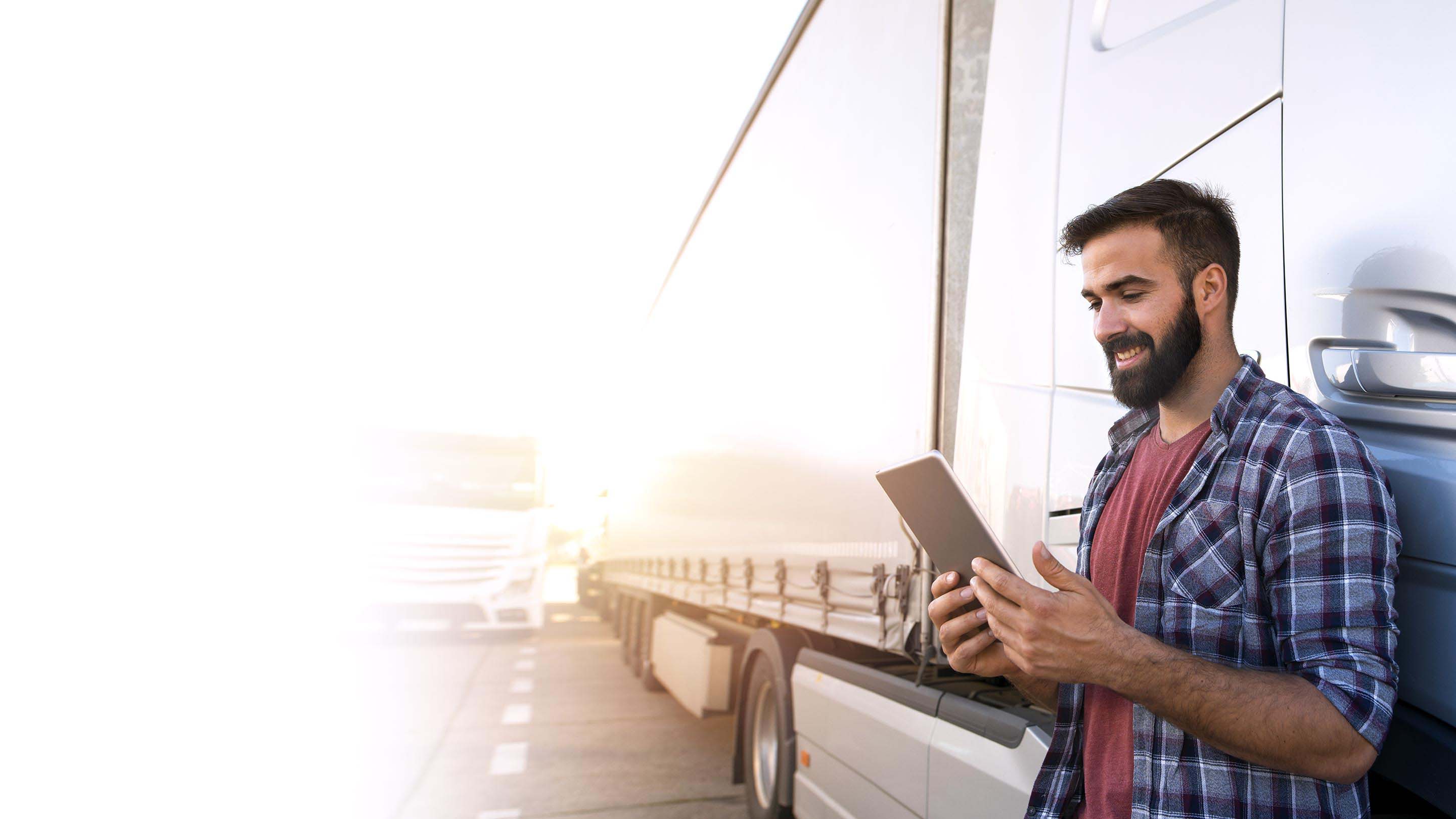 Man smiling while using tablet beside his truck