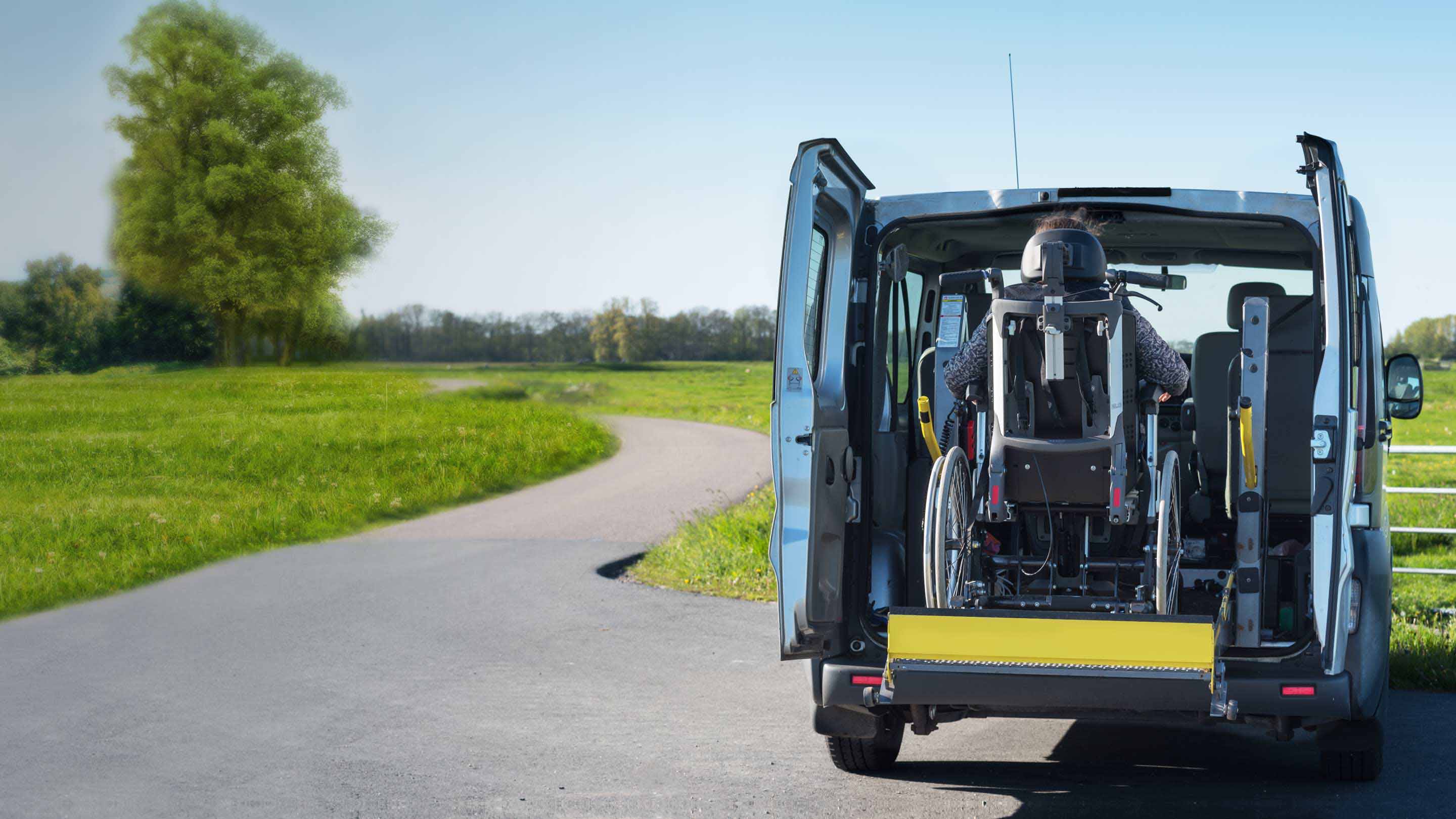 Person in einem Rollstuhl, die hinten in einen Lieferwagen einsteigt.