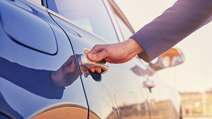 La mano de la persona en la manija de la puerta de un automóvil