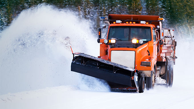 Orange snow plow plowing snow