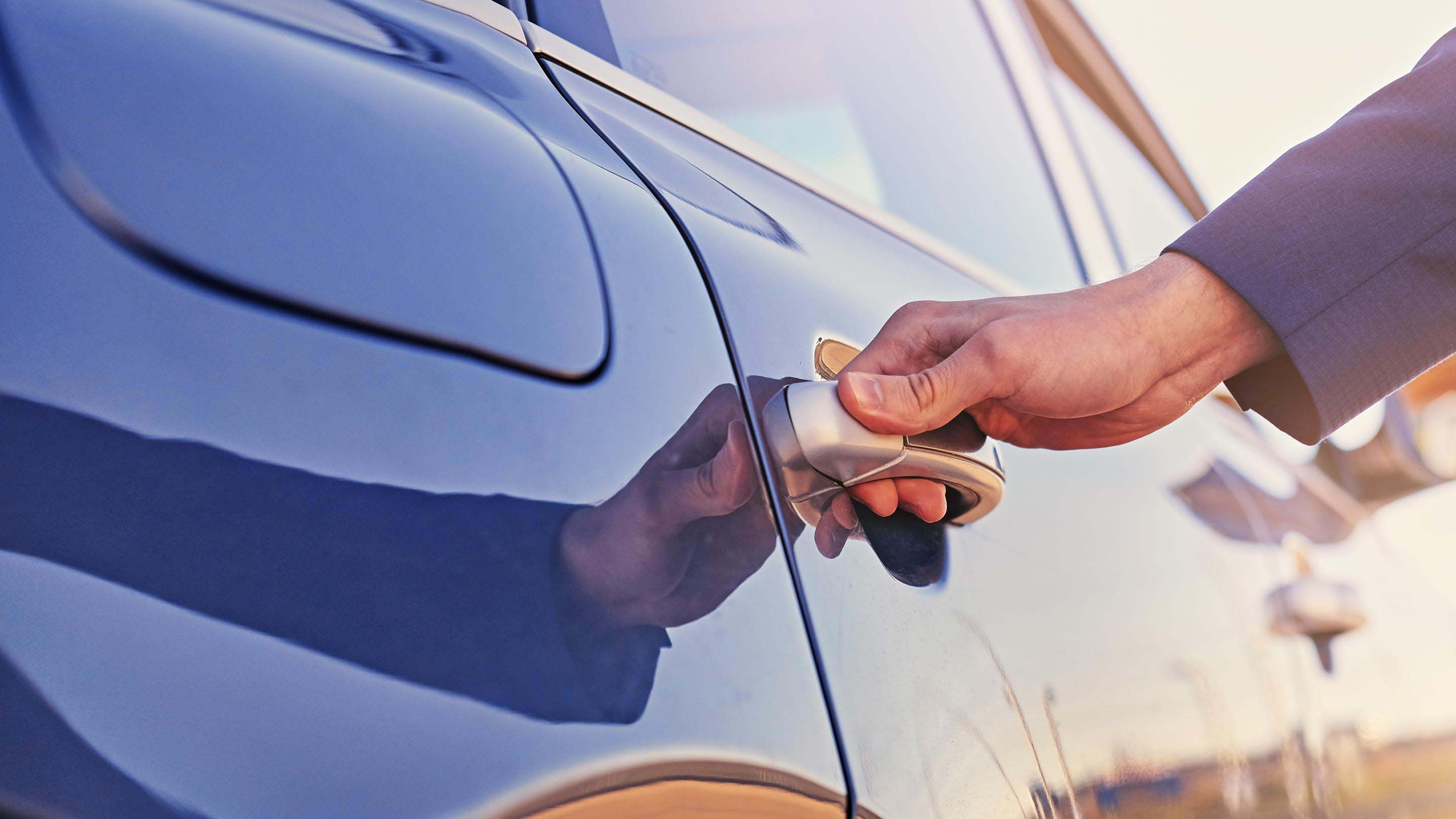 Person's hand on the handle of a car door