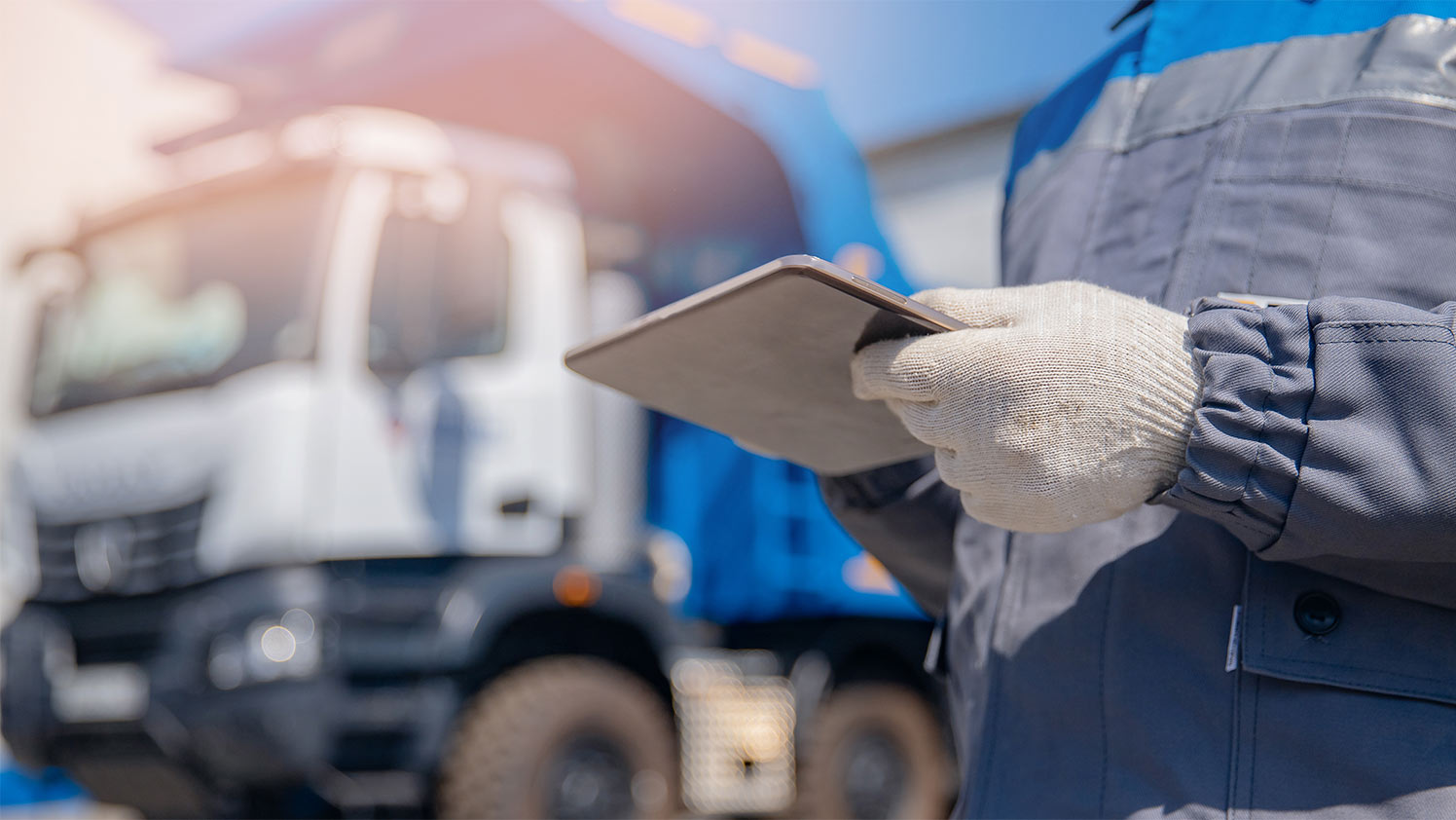 Person standing next to a garbage truck using a tablet
