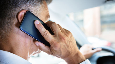 Persoon aan de telefoon in de auto.