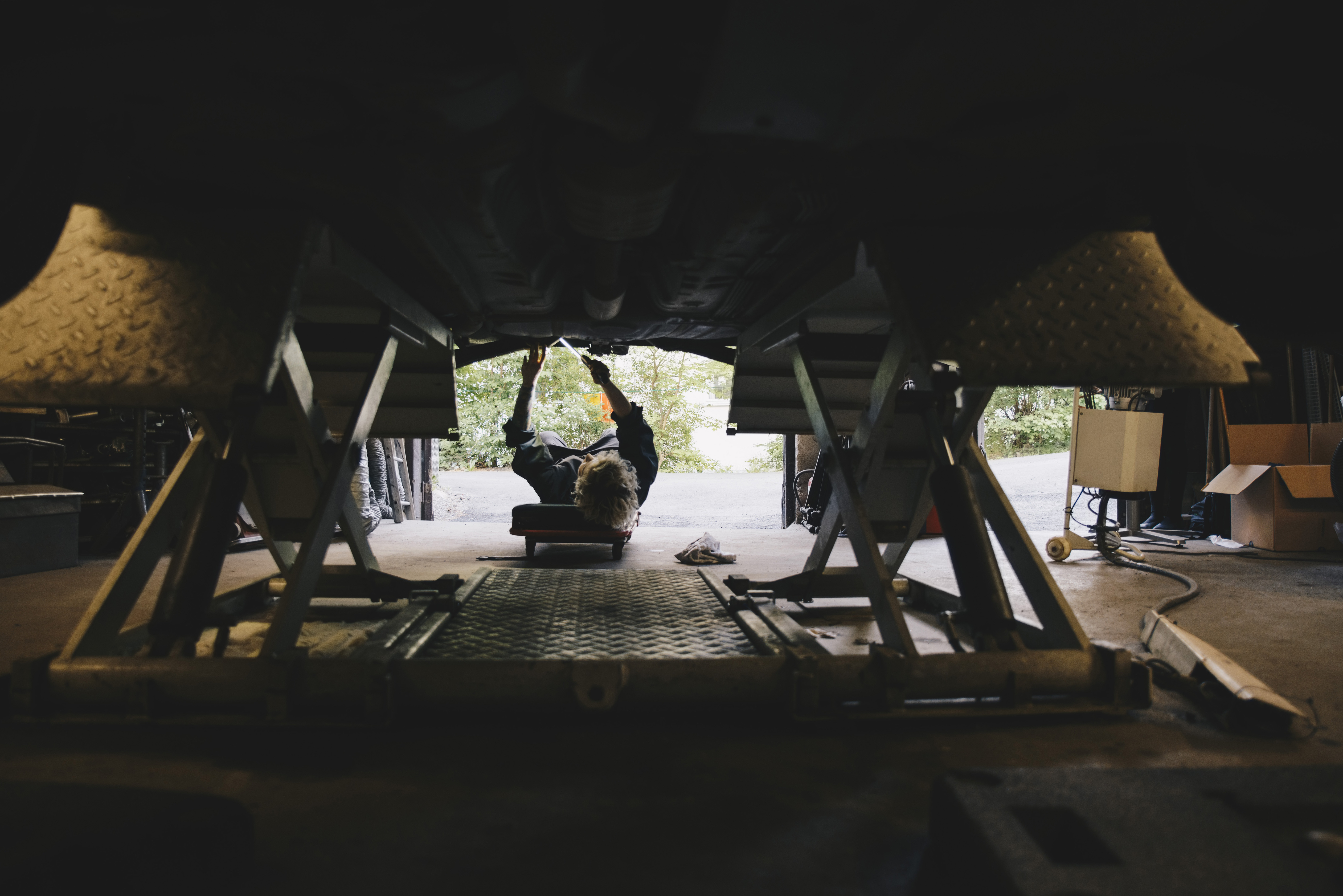Mechanic repairing the underside of a raised vehicle on a garage car lift.