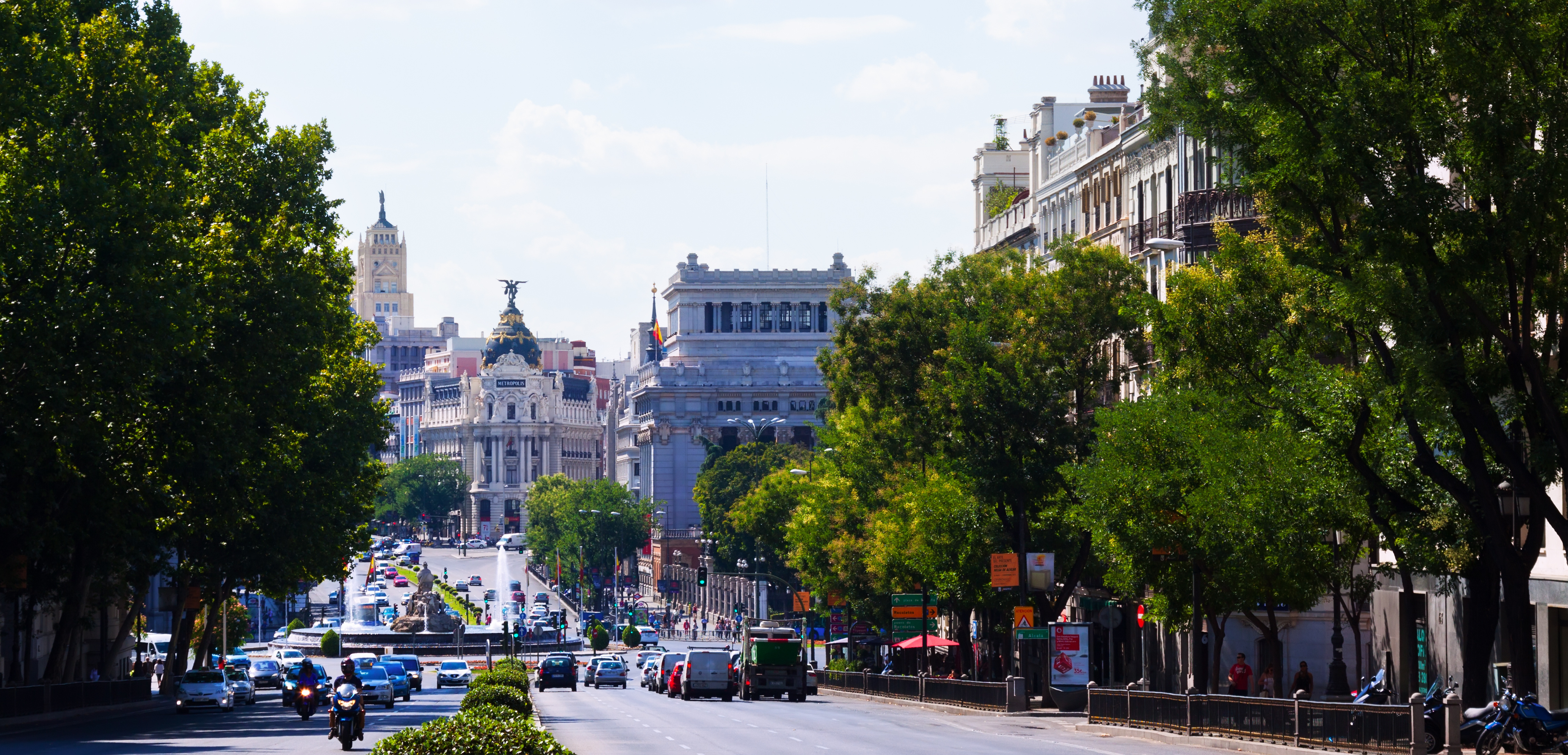 Vista de la Calle de Alcalá desde la Plaza de la Independencia en Madrid, con tráfico de coches y motos y el edificio Metrópolis al fondo