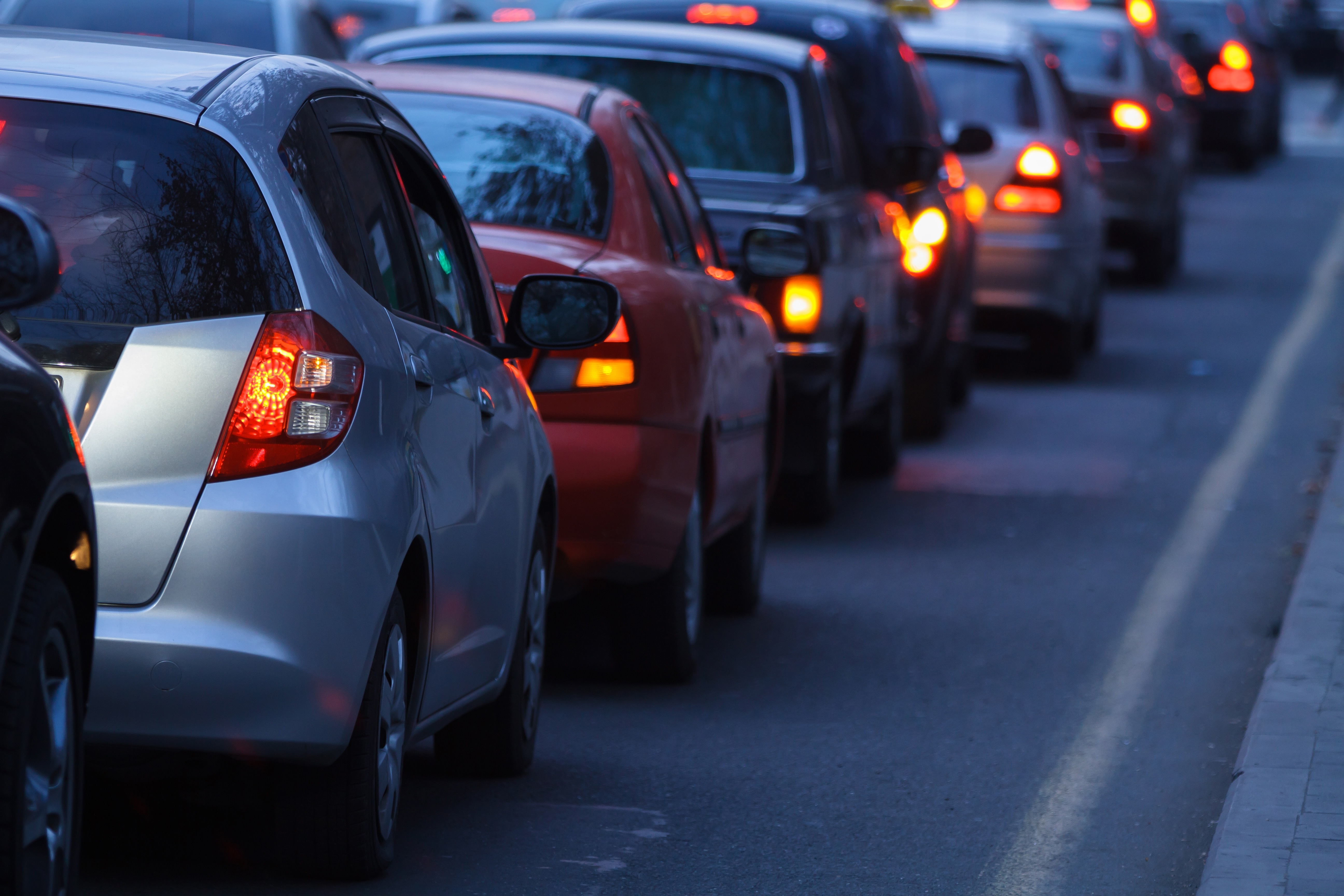 Una fila di automobili incolonnate nel traffico cittadino con le luci di stop rosse accese, a dimostrazione di una forte congestione stradale.