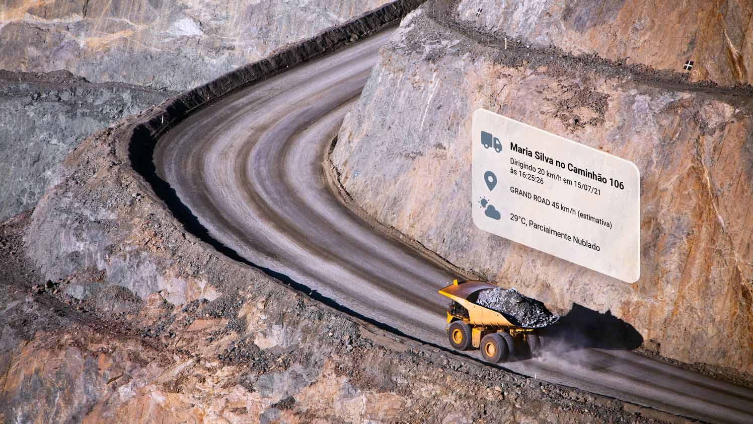 Yellow dump truck driving up a curving dirt road with MyGeotab UI elements above it