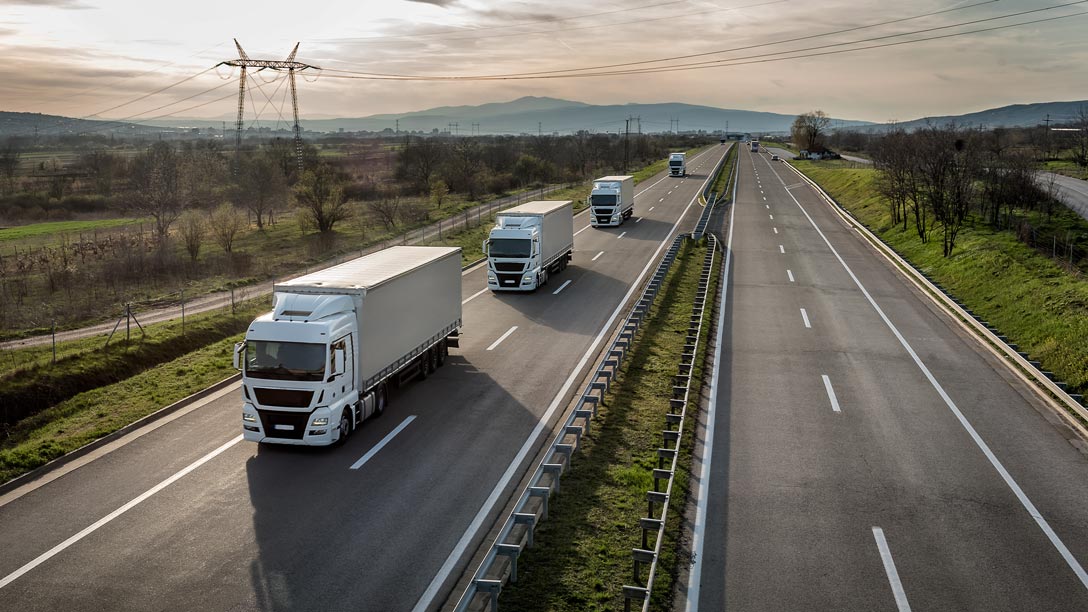 Imagem de três caminhões em uma rodovia