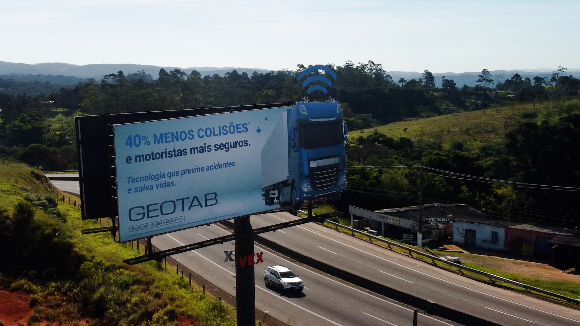 outdoor com um caminhão e uma aplicação de sinal de wifi simbolizando o envio de dados e com uma frase sobre segurança nas estradas