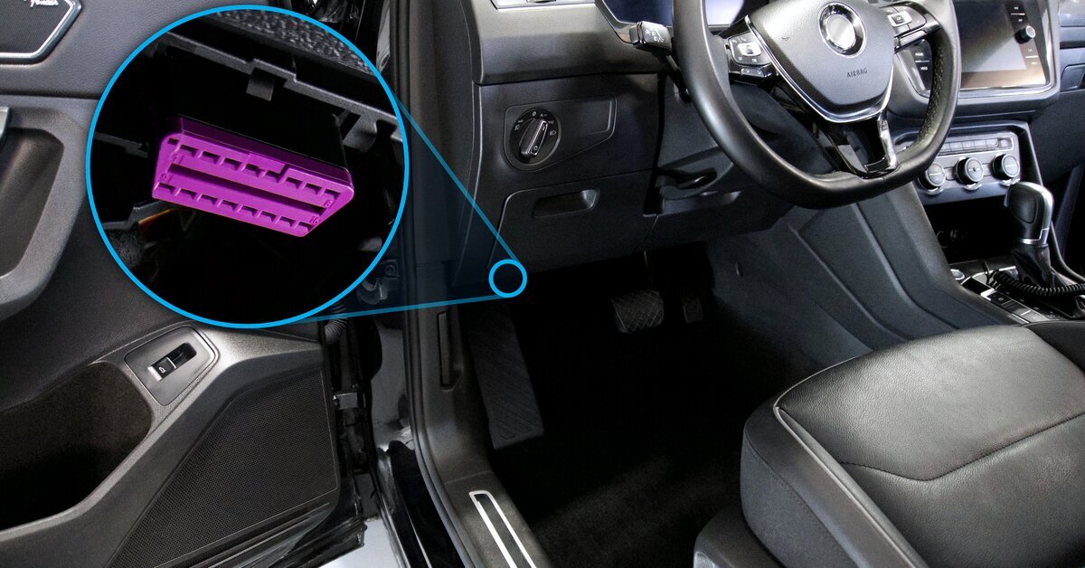 A imagem mostra o interior de um carro que mostra a porta OBD-II (On-Board Diagnostics), localizada geralmente na parte inferior do painel.