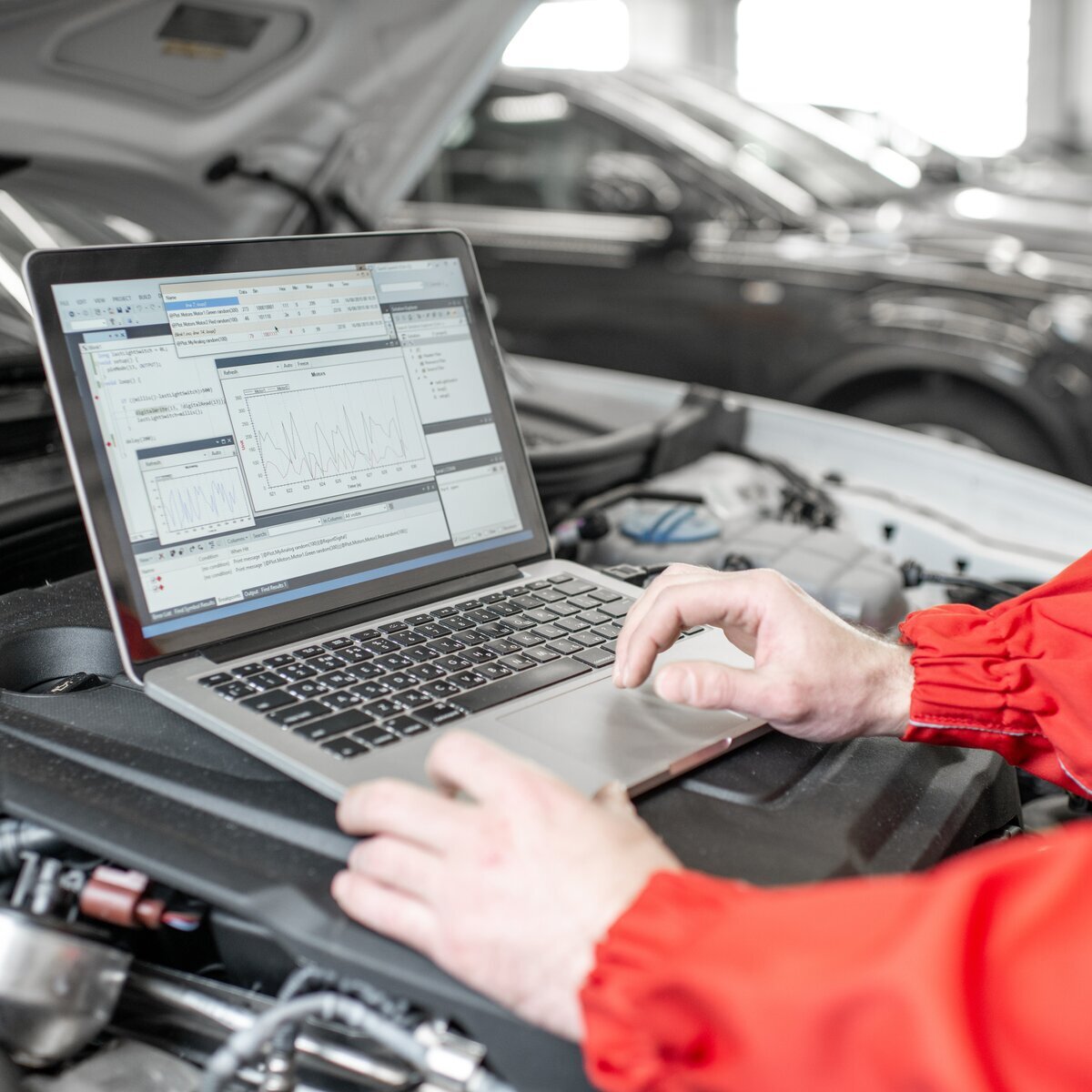 Mecânico utiliza softwares de diagnóstico sobre o motor de um veículo, ilustrando a análise de dados para manutenção preditiva e preventiva da frota.