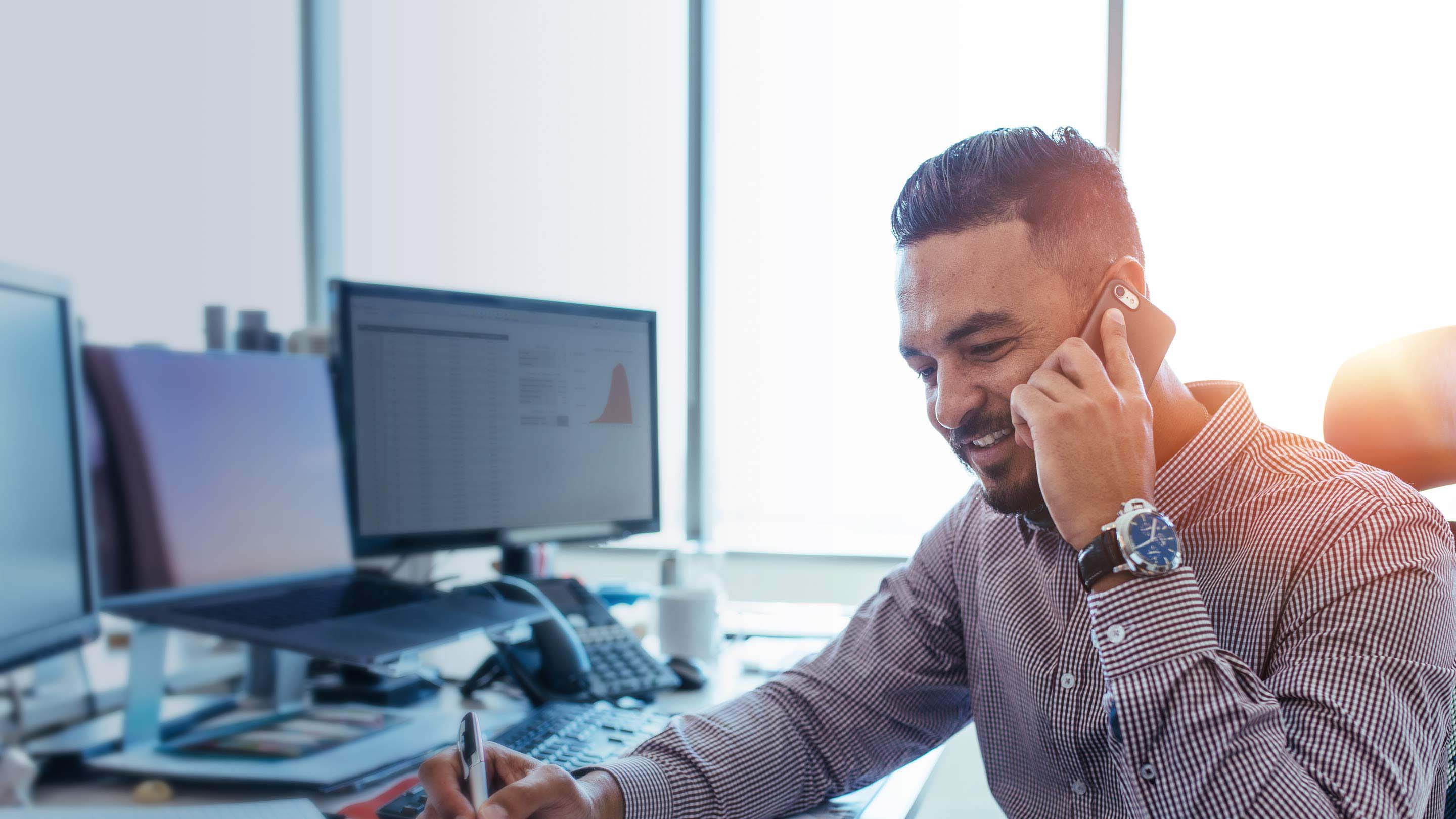 Uomo alla scrivania che lavora e parla al telefono