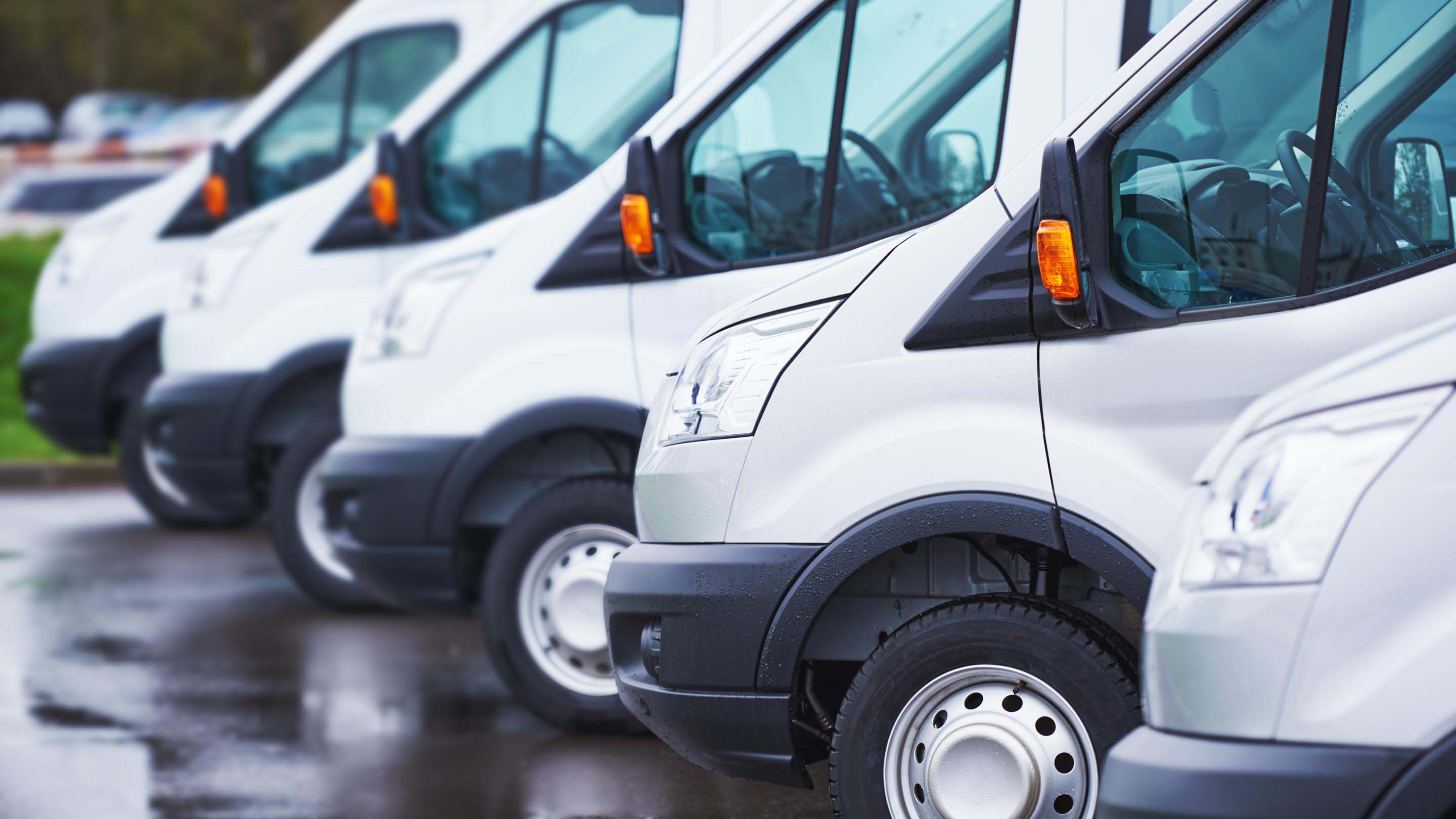 Row of white vans parked next to each other