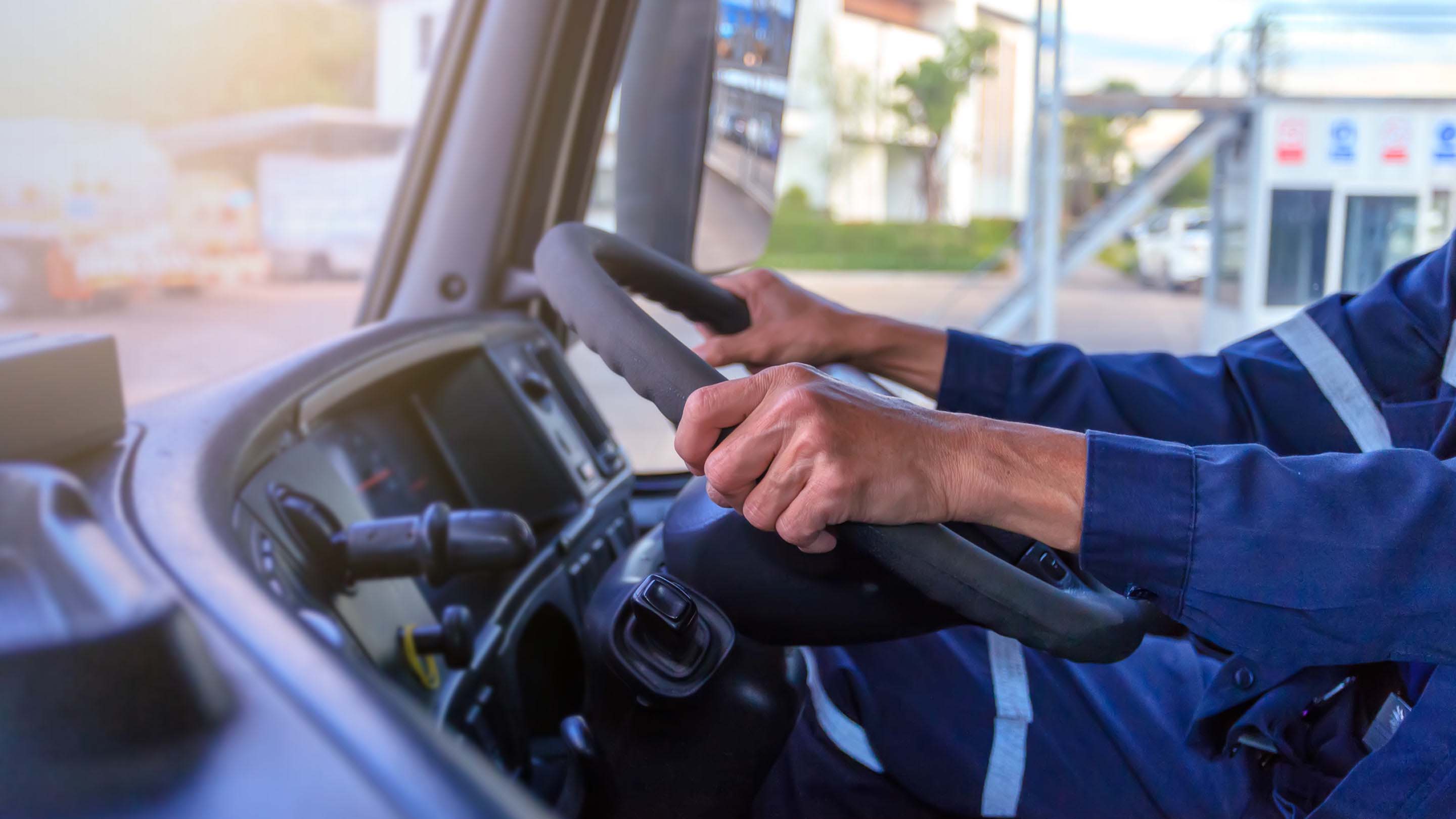 Manos de una persona en el volante de un camión grande y pesado