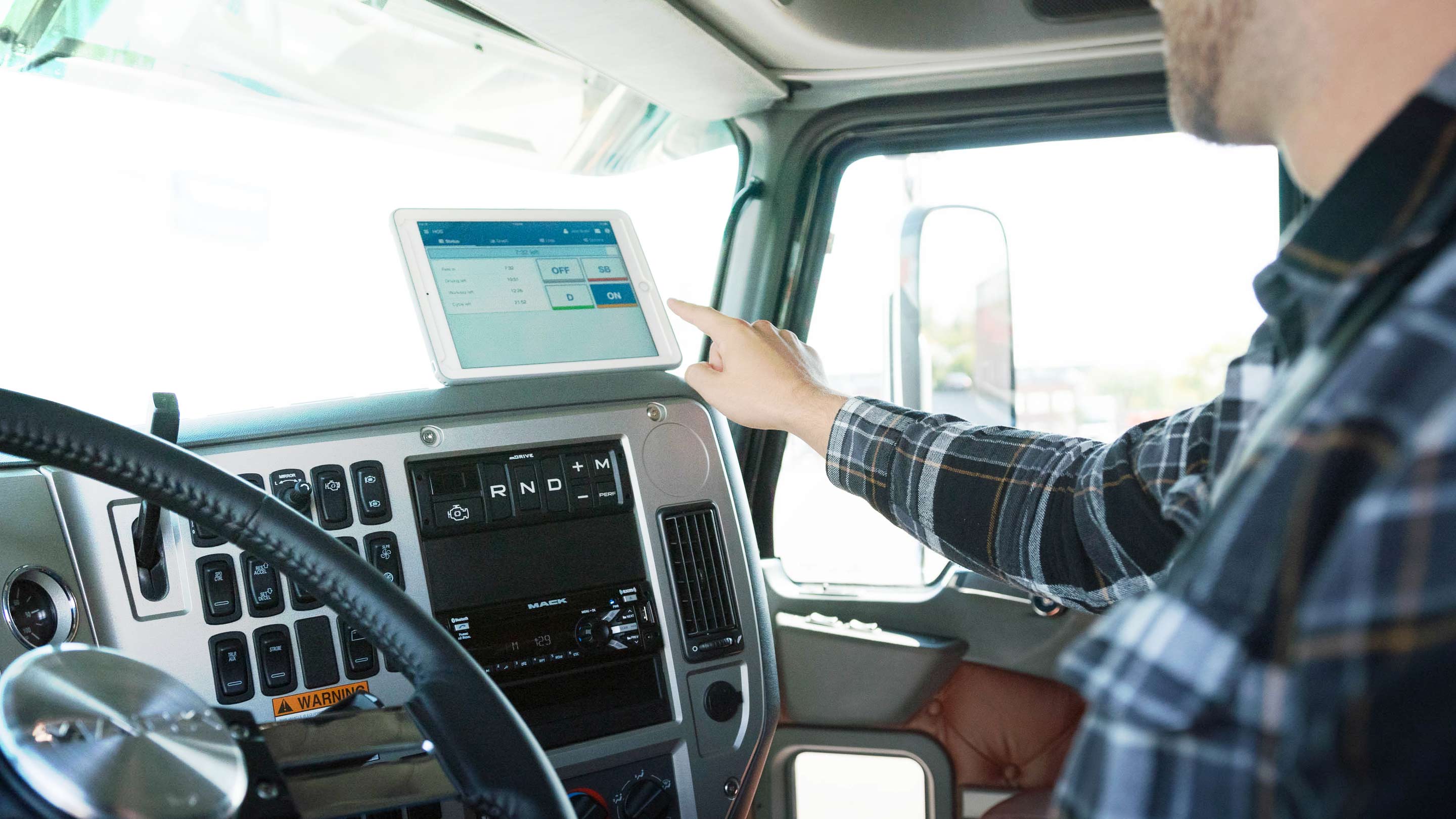 Man in truck with tablet on dashboard showing Geotab Drive UI
