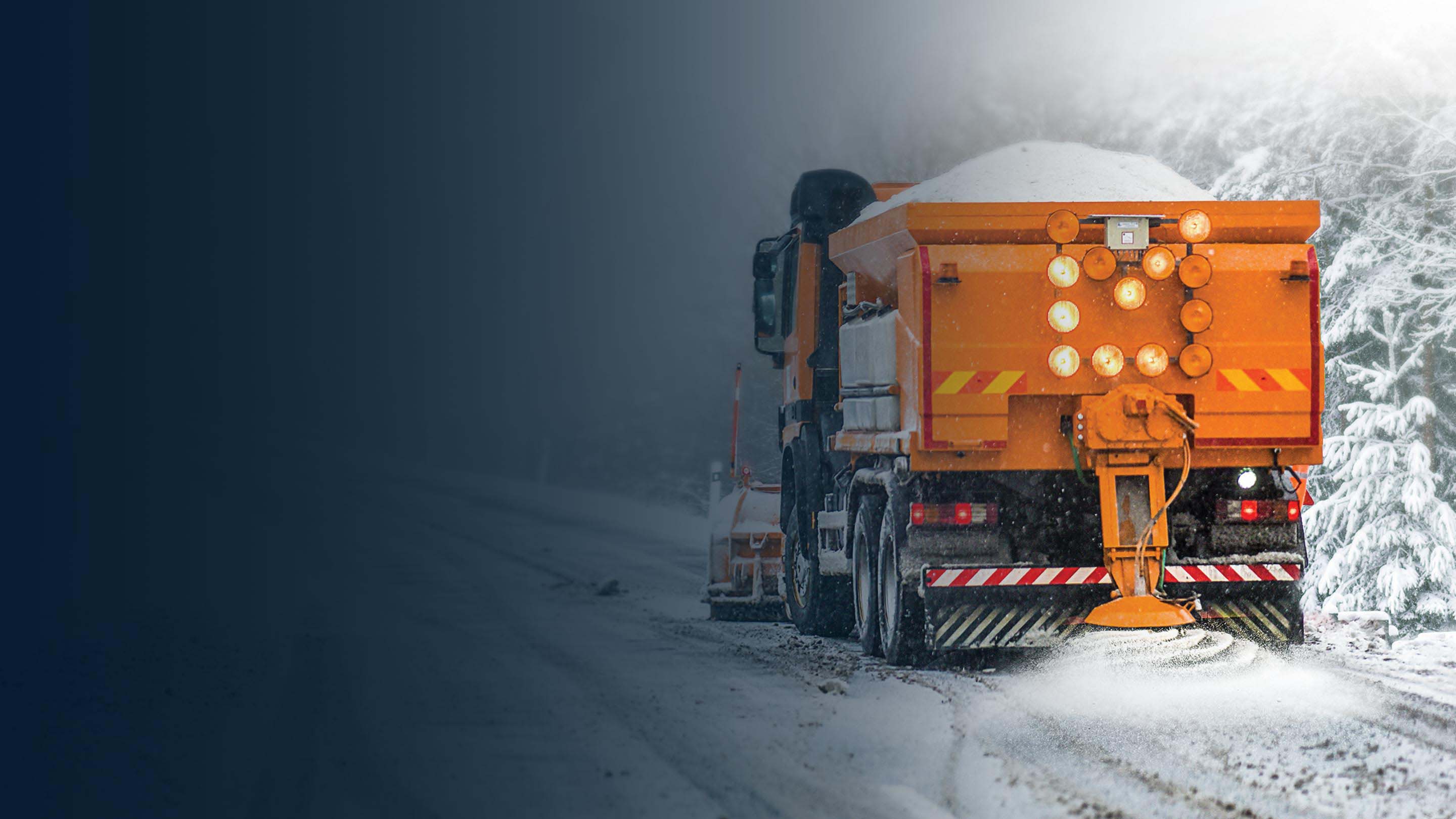 Orange snow plow driving down an empty road