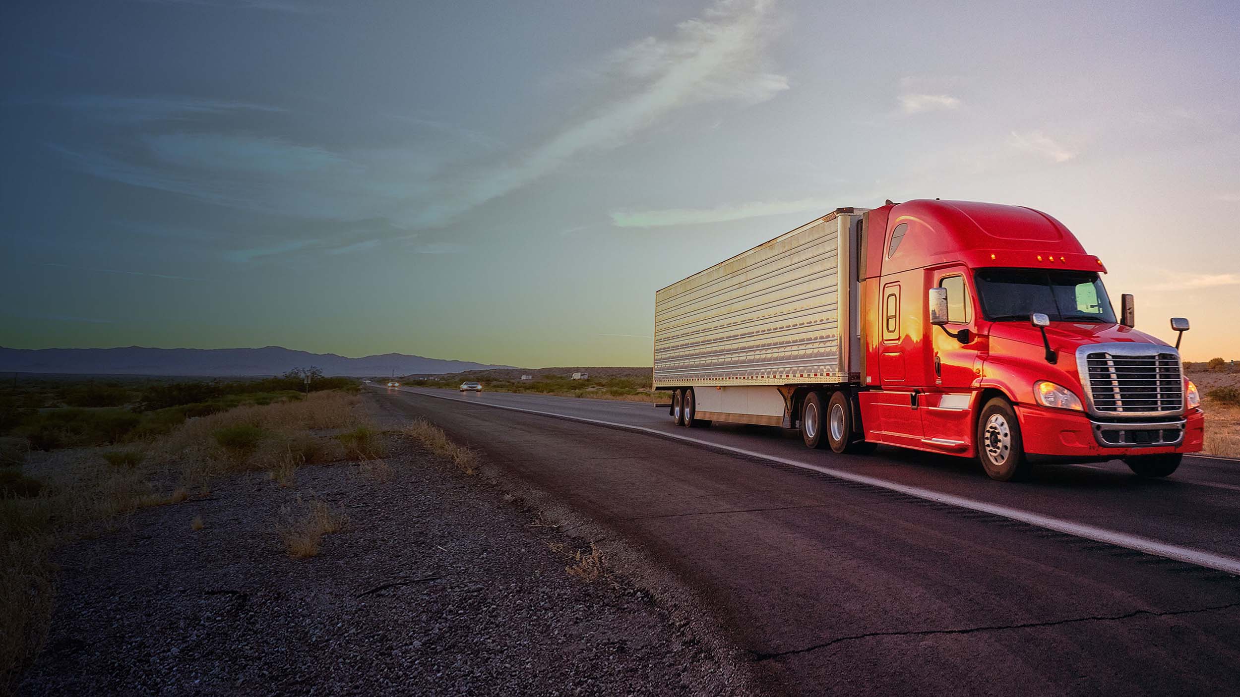 Camion che sfreccia su una strada con un paesaggio arido intorno