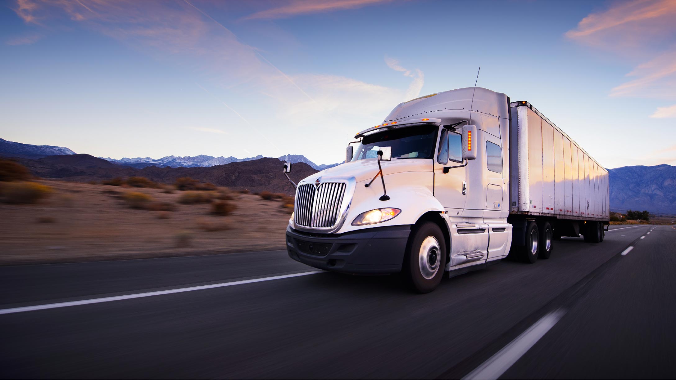 Truck driving on a highway with mountains in the background