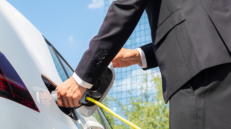 Man in suit plugging in his electric vehicle to charge