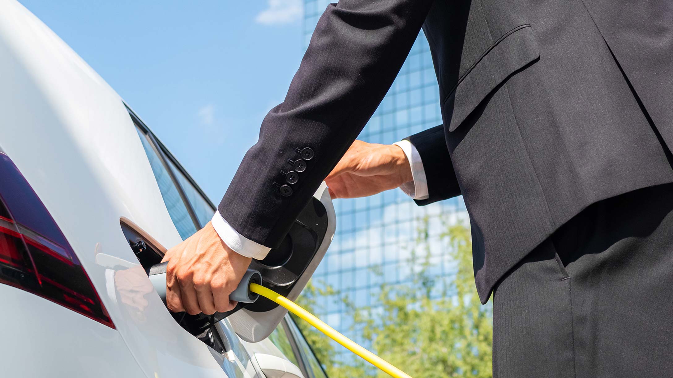 Man in suit plugging in his electric vehicle to charge