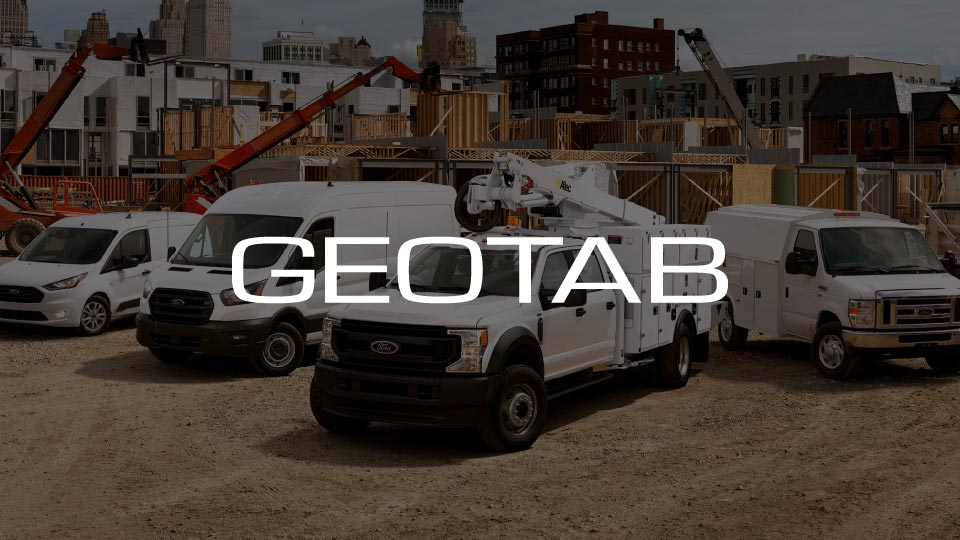 White Ford vehicles at a construction site with a Geotab logo overlay 
