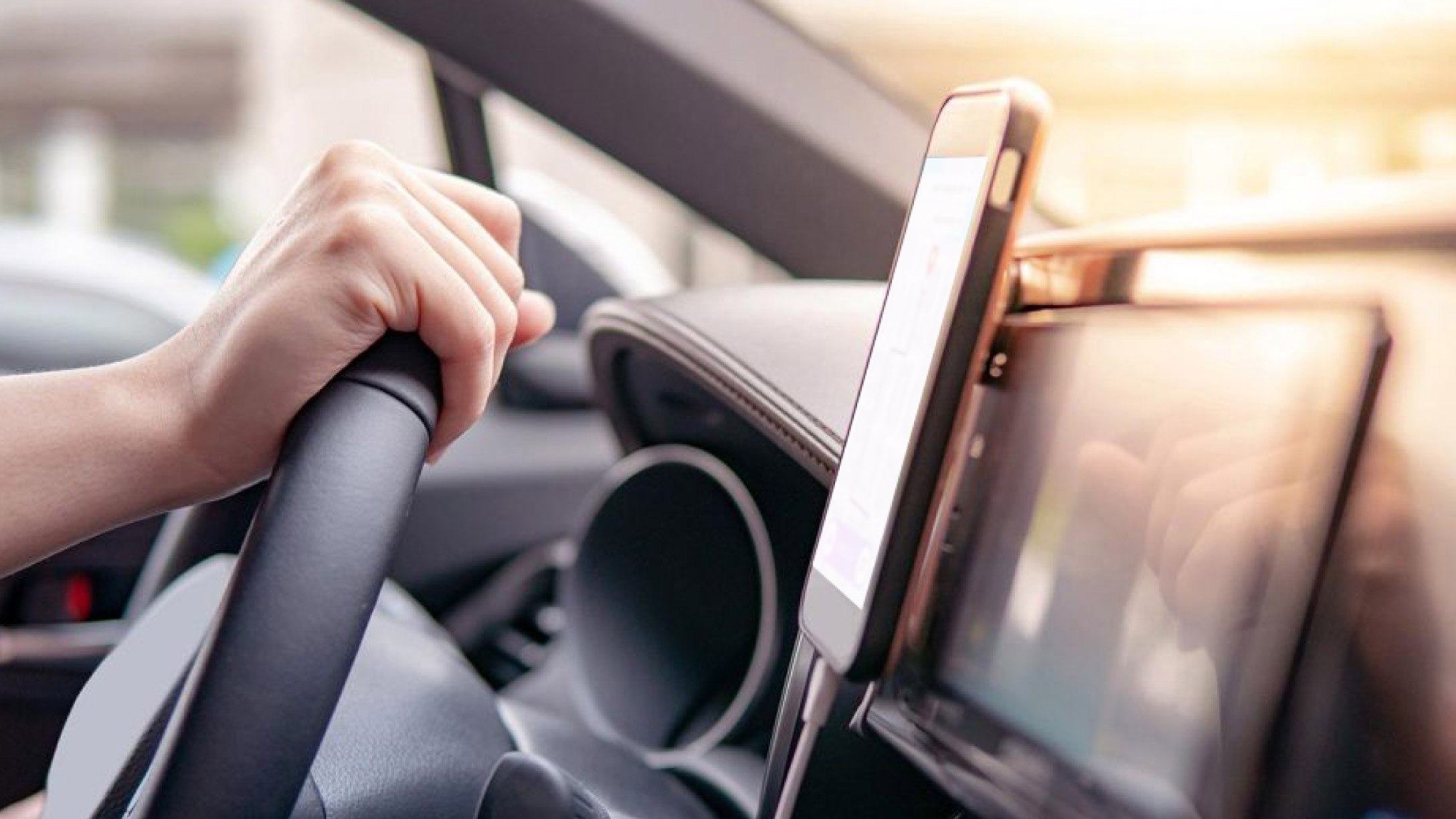 A person driving with a smart phone attached to the dashboard