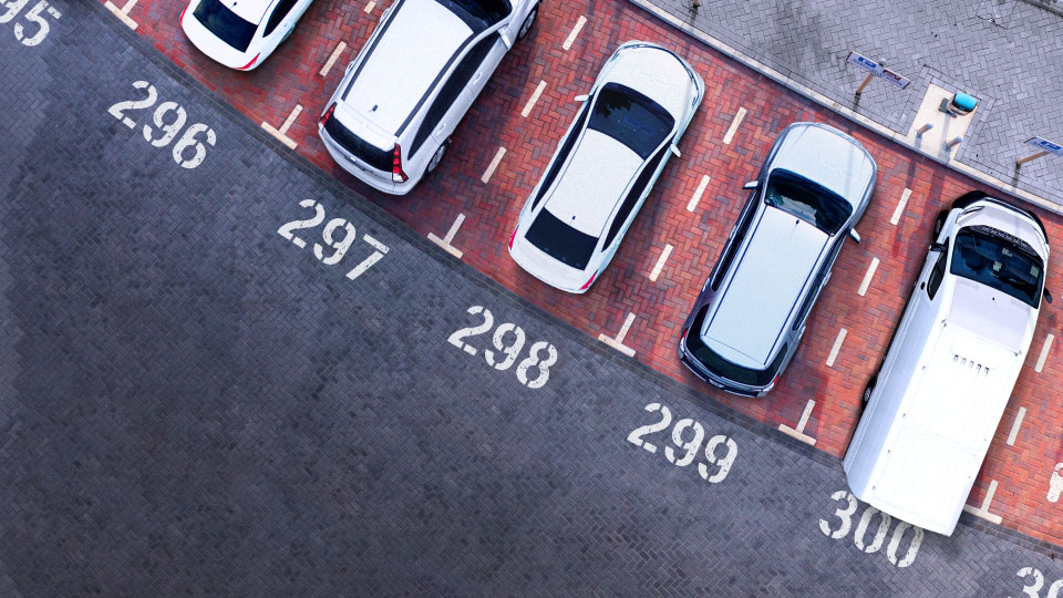 Eine Reihe Fahrzeuge die auf nummerierten Parkplätzen geparkt sind.