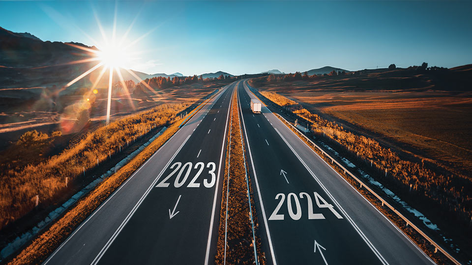 Road with 2024 painted on the asphalt and a truck driving down the road.