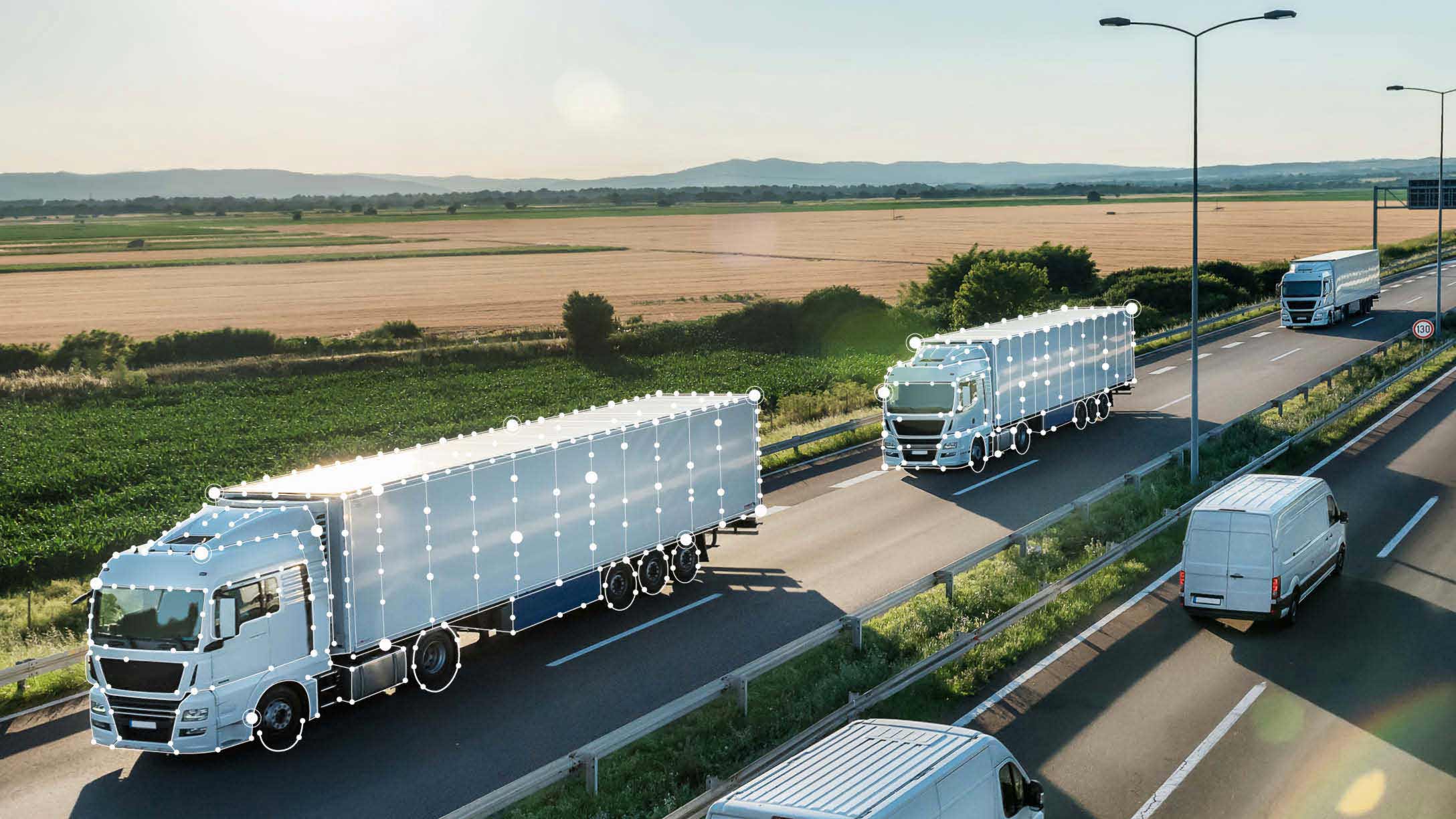 Semi trucks and vans with data points driving on a two-way highway with fields in background