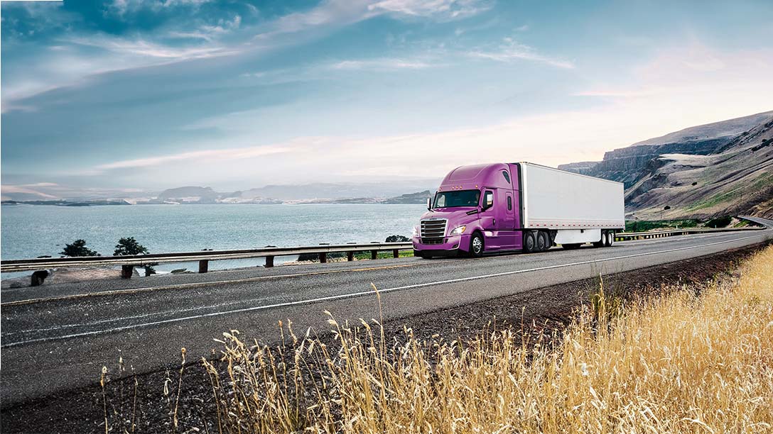 Purple Freightliner truck driving on a highway 