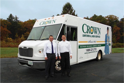Two men standing in front of a Crown Uniform and Linen Service vehicle
