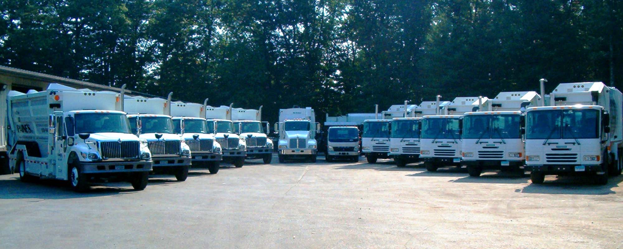 A lineup of white waste and recycling vehicles