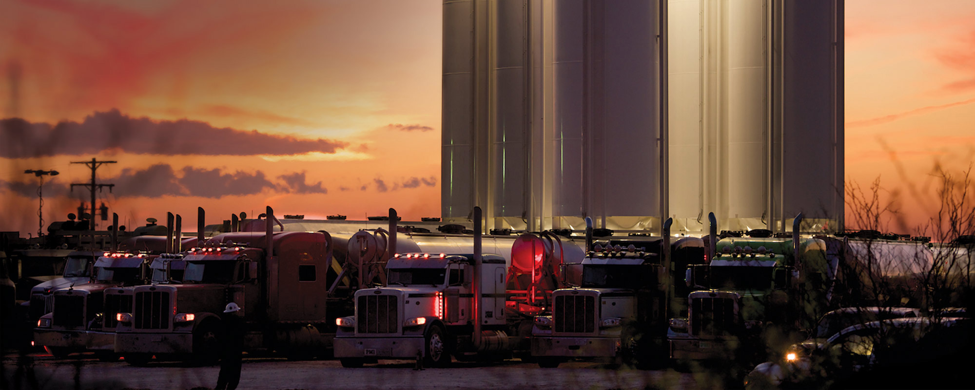 Oil trucks with oil storage containers behind it and logo in the left hand corner. 