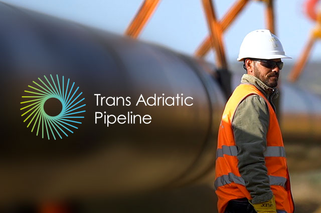 Worker at a construction site standing beside Trans Adriatic Pipeline logo