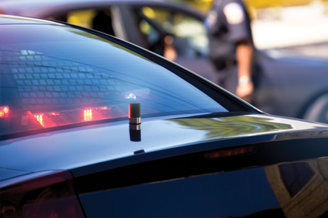 Back of black police car with red and blue lights flashing. 