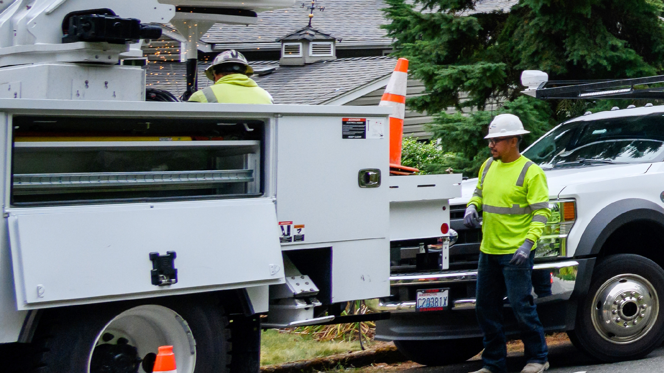 a man next to a truck wearing green shirt with a hardhat on