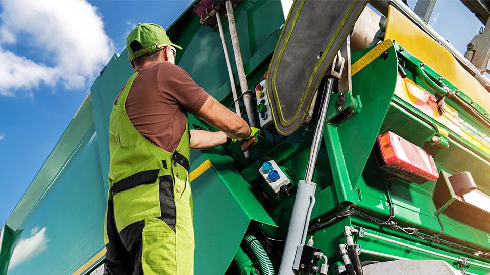 person holding on to a waste management truck