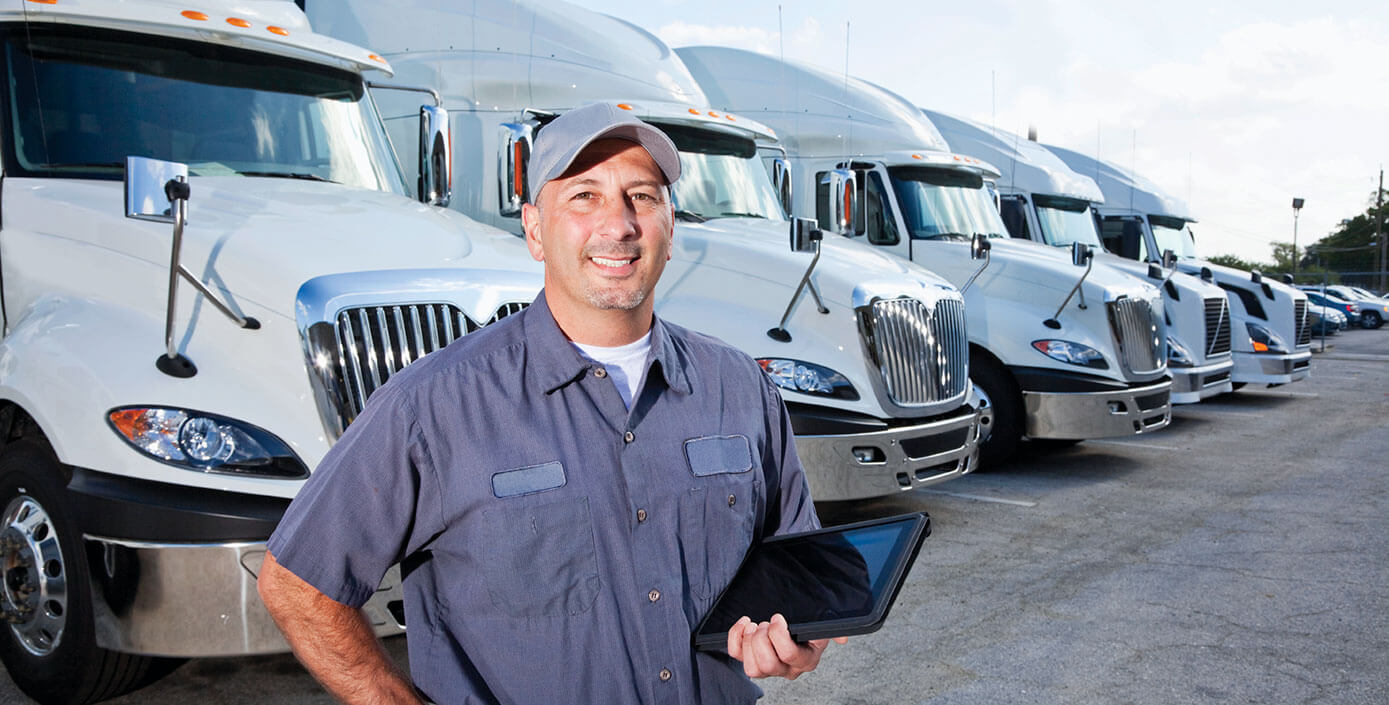 Fleet manager smiling in front of four transportation vehicles