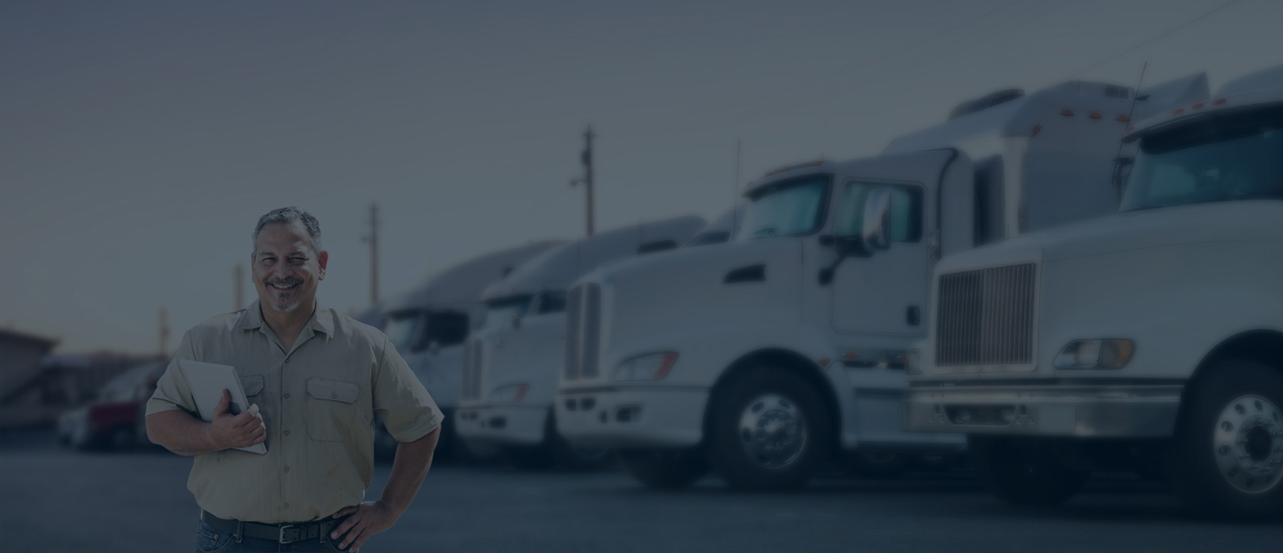 Truck manager smiling in front of transportation trucks