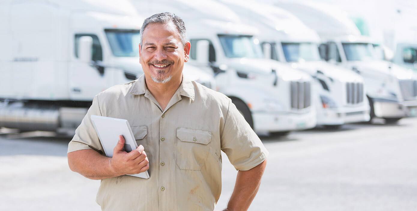 Truck manager smiling in front of transportation trucks