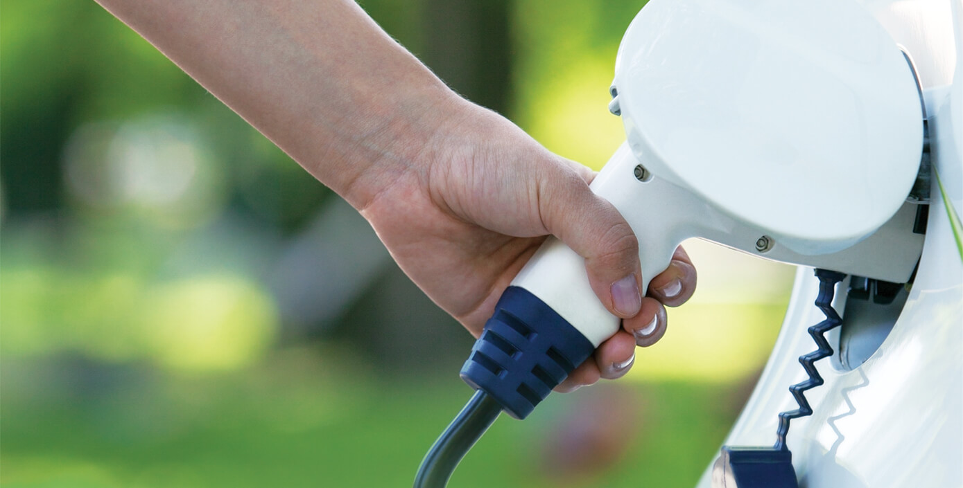 Hand steckt ein Elektrofahrzeug an das Ladegerät