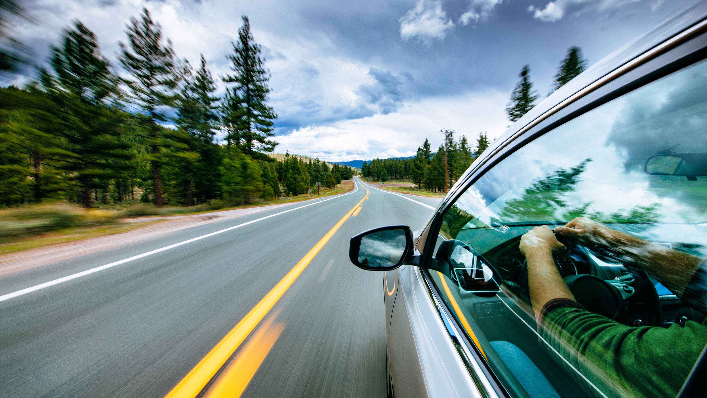 Photo of a person driving down the road in a silver car