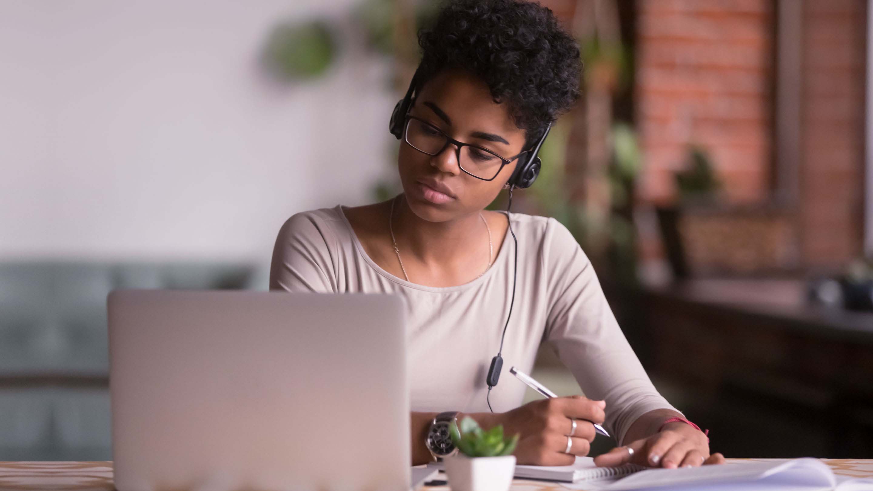 Woman wearing headphones connected to laptop
