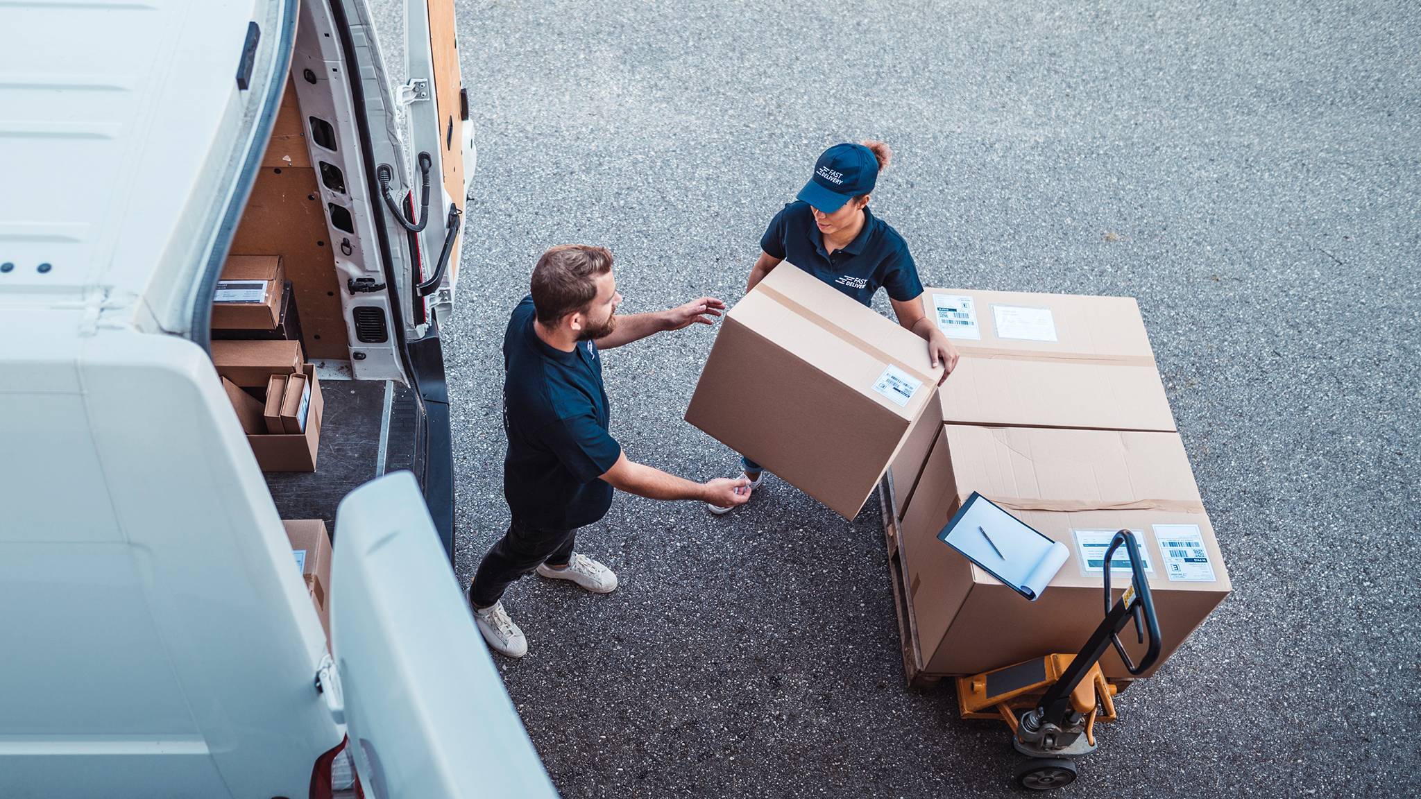 Two delivery workers loading parcels into a van.