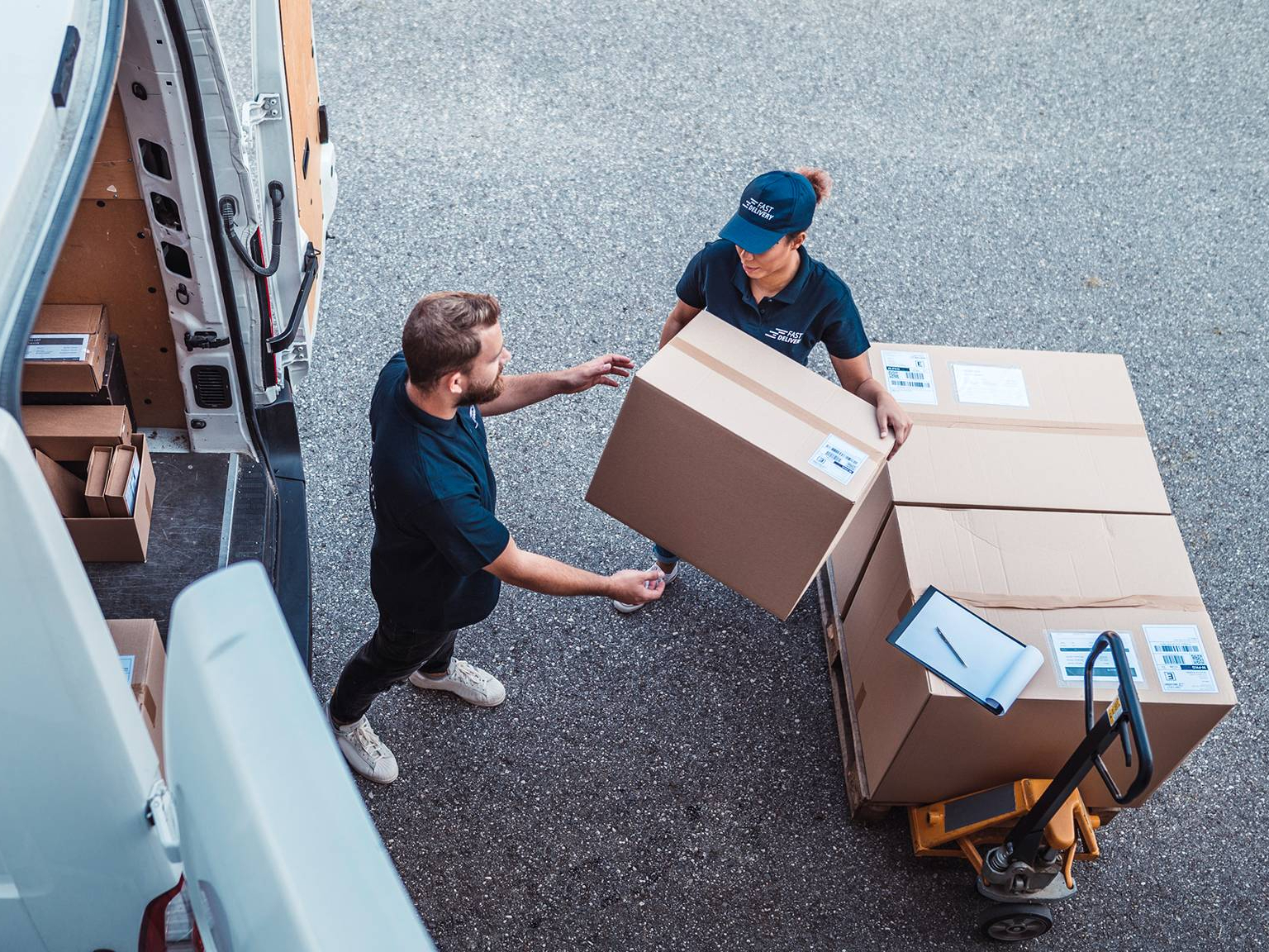 Two delivery workers loading parcels into a van.