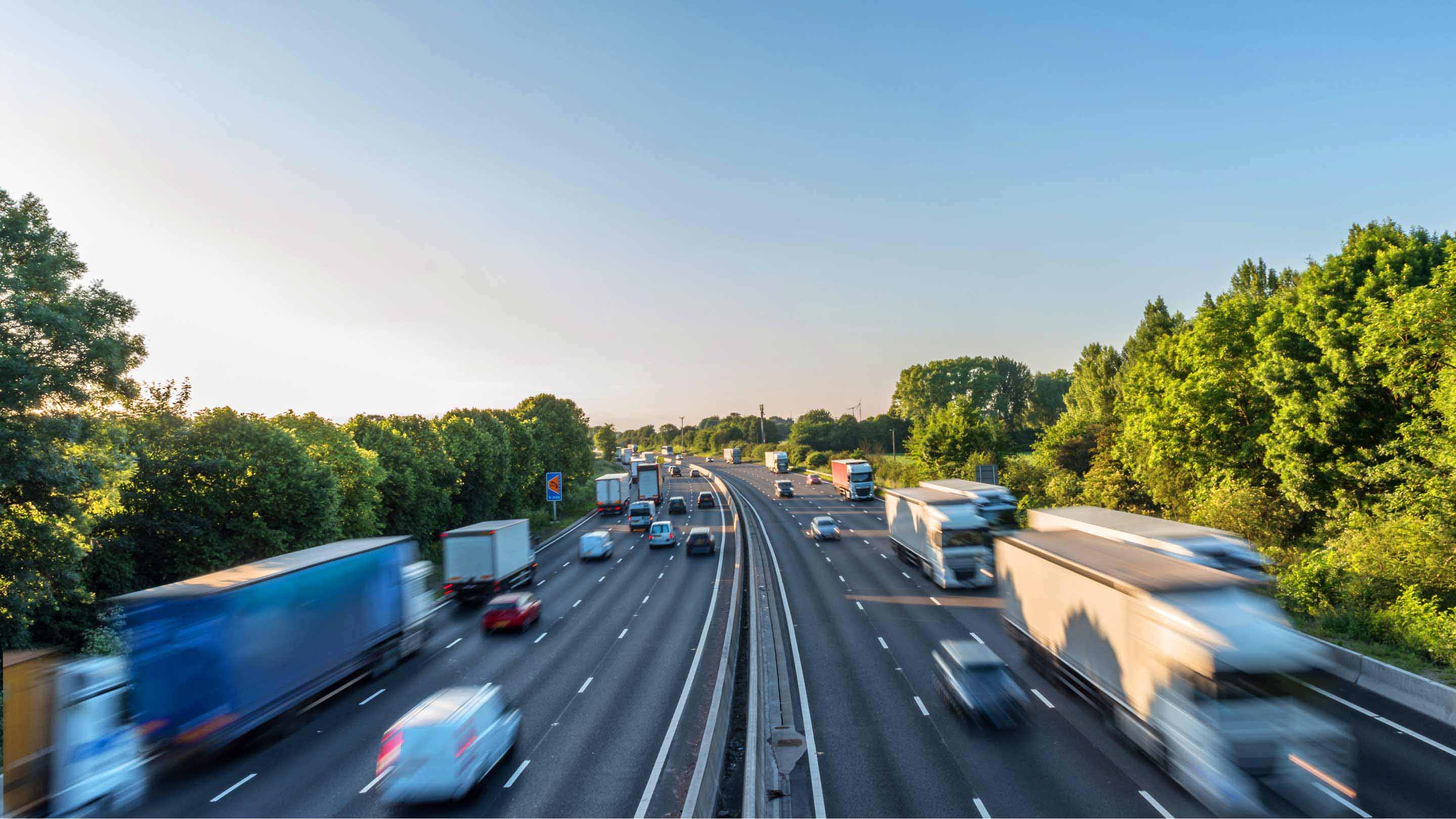 Imagen de una gran autopista de cinco carriles de doble sentido con coches circulando por ella