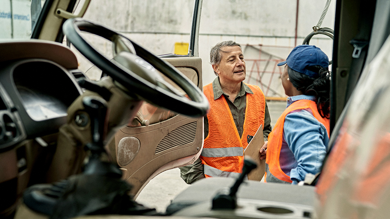 Colleagues having a pleasant discussion beside a parked truck 